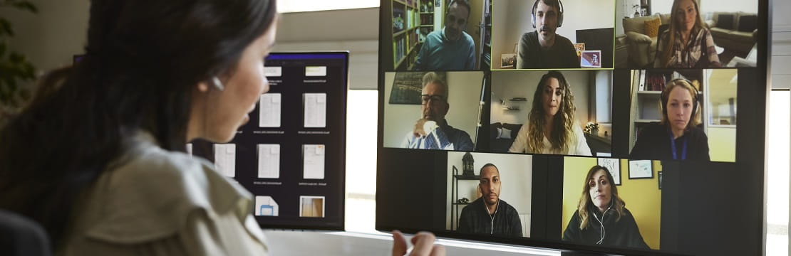 Woman sits in front of a computer on a video conference call. 